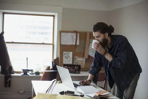 Young man having coffee while using laptop at workshop Stock Photos