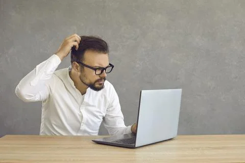 Young man having computer problem and looking at screen of his laptop in Stock Photos