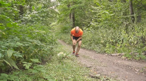 Young Man Having a Cramp While Jogging. Stop And To Massage the Knee. Man Run Stock-Footage 66436727