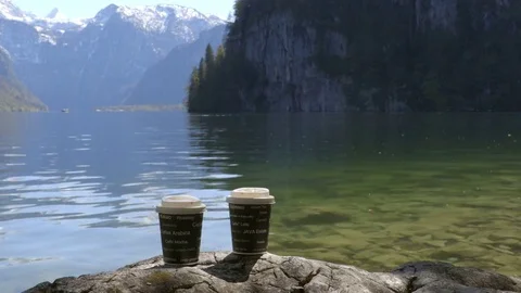Young man having a cup of coffee in the morning next to the mountains lake. Stock Footage 75131016