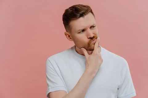 Young man having doubts, looking aside and thinking Foto stock