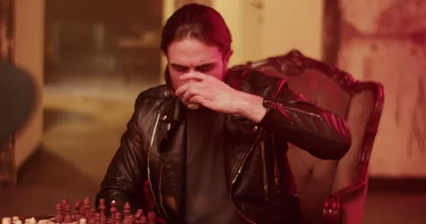 Young man having drink while playing chess with friend Stock Footage 260560124