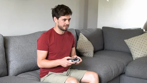 Young man having fun playing games console at home Stock Footage 92256995