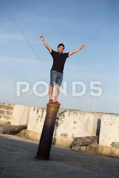 Young man having fun standing on a metal pole Stock Photos