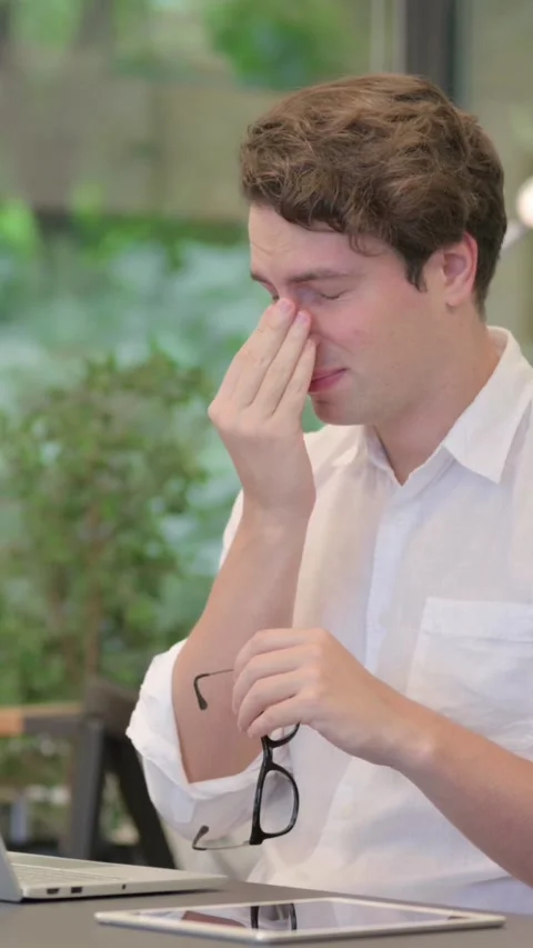 Young Man having Headache while Working on Laptop in Modern Office, Vertical Stockbeeldmateriaal 340038722