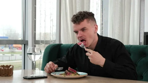 A young man is having lunch in a restaurant. Vidéo 200841023