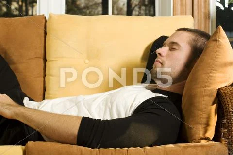 Young man having a nap on couch in living room Stock Photos