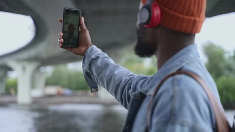 Young man having online talk and waving in front of phone while standing Stock Footage 161745920
