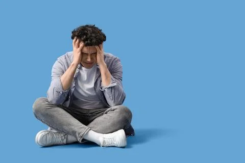 Young man having panic attack on blue background Stock Photos