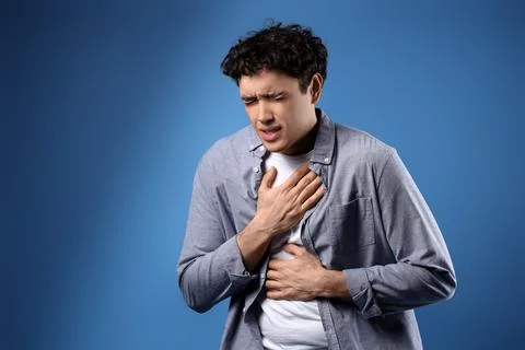 Young man having panic attack on blue background Stock Photos