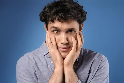 Young man having panic attack on blue background, closeup Stock Photos