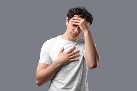 Young man having panic attack on grey background Stock Photos