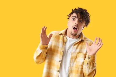 Young man having panic attack on yellow background Stock Photos