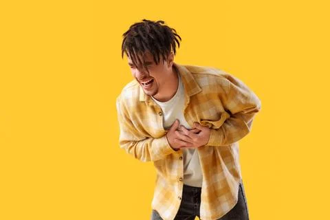 Young man having panic attack on yellow background Stock Photos