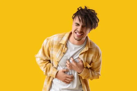 Young man having panic attack on yellow background Stock Photos