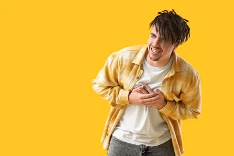Young man having panic attack on yellow background Stock Photos