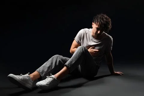 Young man having panic attack on black background Stock Photos