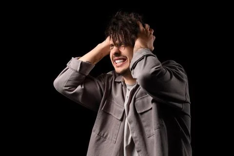 Young man having panic attack on black background Stock Photos