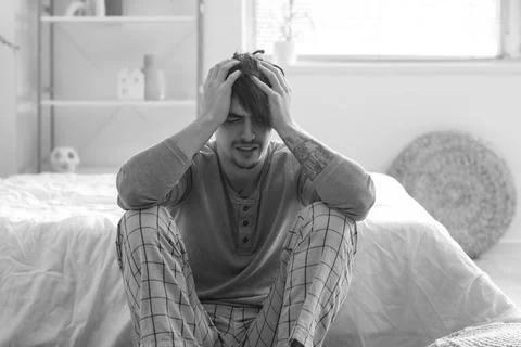 Young man having panic attack in bedroom Stock Photos