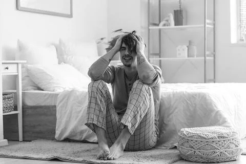 Young man having panic attack on floor in bedroom Stock Photos