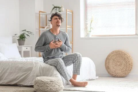 Young man having panic attack in bedroom Stock Photos