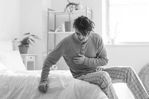 Young man having panic attack in bedroom Stock Photos