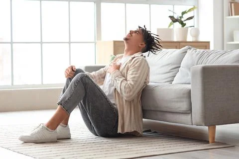 Young man having panic attack near sofa at home Stock Photos