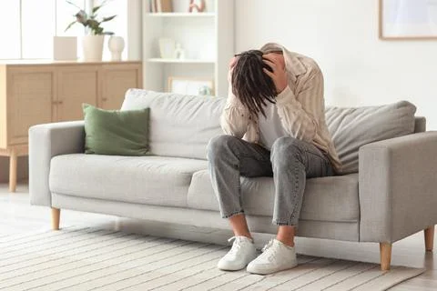 Young man having panic attack on sofa at home Stock Photos