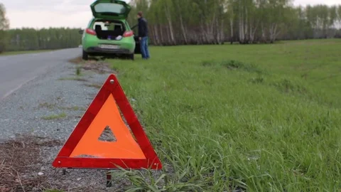 Young man having problem with car, red triangle on the rural road Stock Footage 75919704