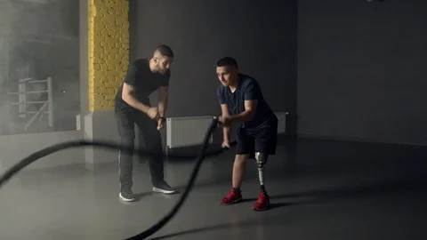 Young man having prosthetic leg using battle ropes in gym Stock Footage 125533139