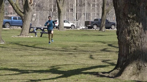 Young man having a run in the park on a sunny spring day. 4K UHD. Stock Footage 74857410