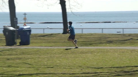 Young man having a run in the park on a sunny spring day. 4K UHD. Stock Footage 74857656