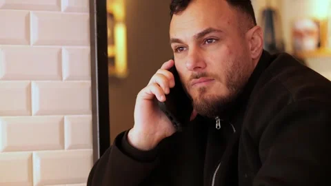 Young Man Having Serious Conversation on Smartphone in Modern Cafe Vídeo Stock 332554008