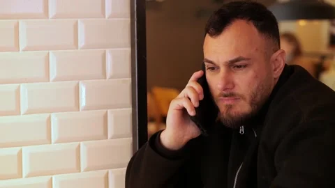 Young Man Having Serious Conversation on Smartphone in Modern Cafe Vídeo Stock 332554010