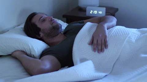 Young man having trouble sleeping, tossing and turning Stockbeeldmateriaal 47855061