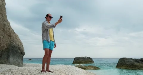 Young man having video call on smartphone at the beach, 5g concept. Stock Footage 156417221