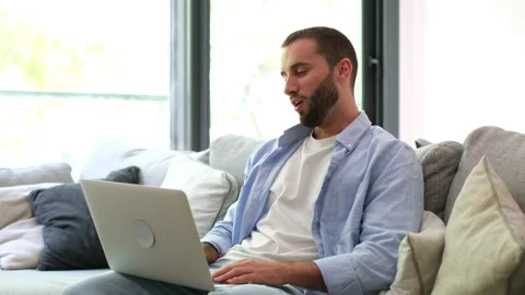 Young man having a video call on a laptop at home Stock Footage 335588564