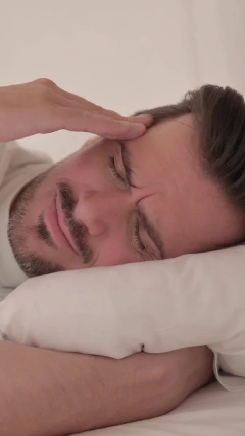 Young Man with Headache Lying in Bed on Side, vertical video Video stock 328565266