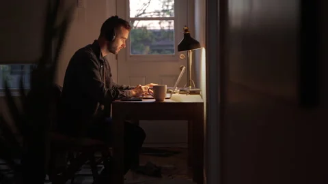 Young Man in Headphones Freelancer Using Laptop in the Evening at home Stock Footage 139725883
