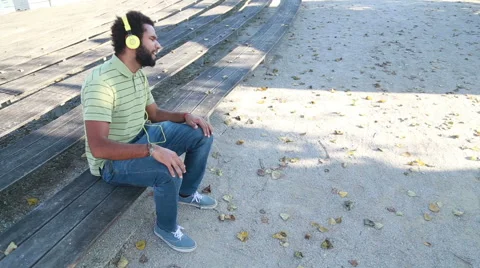 Young man with headphones listening to music and singing at park Stock Footage 59554988