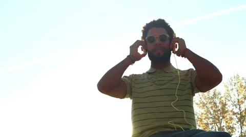 Young man with headphones listening to music at park Stock Footage 59555373