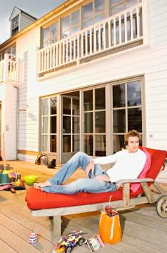 Young man with headphones lying on a deck chair Stock Photos