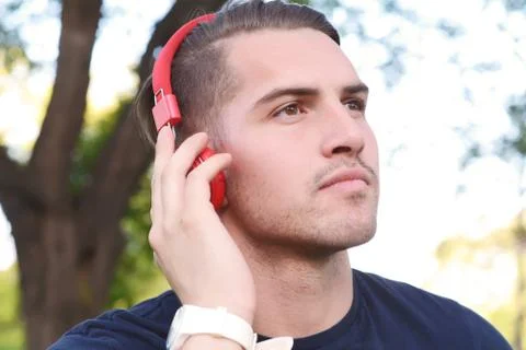 Young man with headphones in a park. Stock Photos
