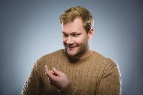 Young man with a headset coming gesture on gray background Stock Photos