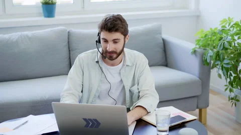 Young man with headset having videocall at home Stock Footage 142537148