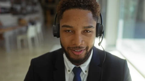 Young man with headset working in an office wearing a suit and tie, smiling.. Vidéo 301138167