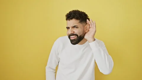 Young man hears gossip, hand to ear, basking in juicy rumor on yellow. deaf.. Stock Footage 271084806
