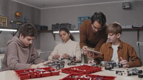 Young Man Helping Kids With Robots Stock Footage 203821164