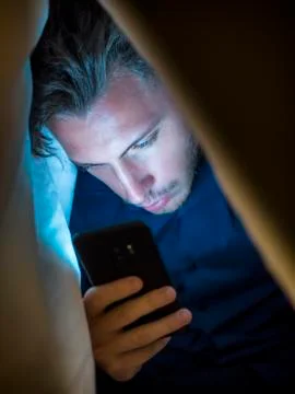 Young man hiding while using a mobile phone Stock Photos