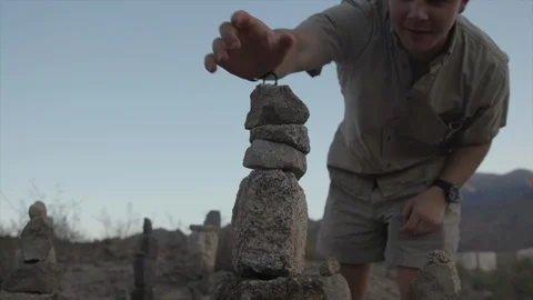 Young Man on Hike Stacking Rocks in Desert Mountains Stock Footage 95932321